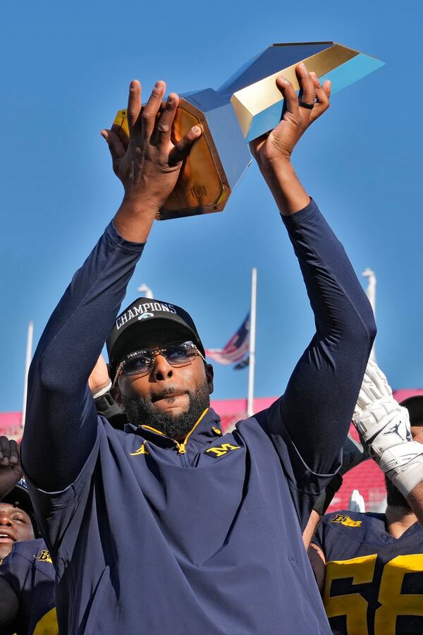 Michigan head coach Sherrone Moore holds up the trophy after defeating Alabama to win the ReliaQuest Bowl NCAA college football game Tuesday, Dec. 31, 2024, in Tampa, Fla. (AP Photo/Chris O'Meara)