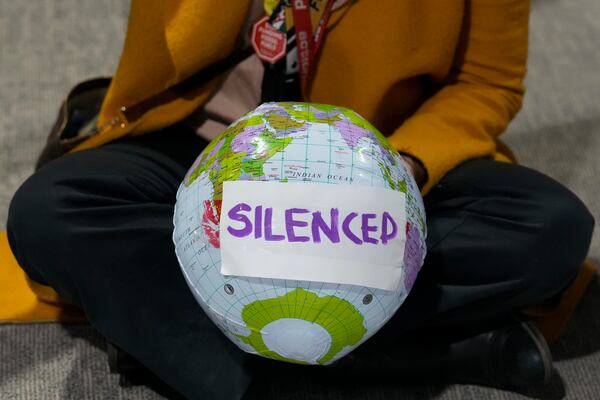 An activist holds a globe that says silenced during a demonstration during the COP29 U.N. Climate Summit, Saturday, Nov. 16, 2024, in Baku, Azerbaijan. (AP Photo/Rafiq Maqbool)