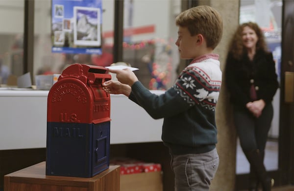 This image released by Disney shows a boy mailing a letter to Santa in a scene from “Dear Santa, The Series." (Disney via AP)