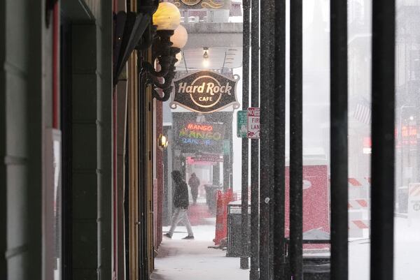 People walk on Bourbon Street during a very rare snowstorm in New Orleans, Tuesday, Jan. 21, 2025. (AP Photo/Gerald Herbert)