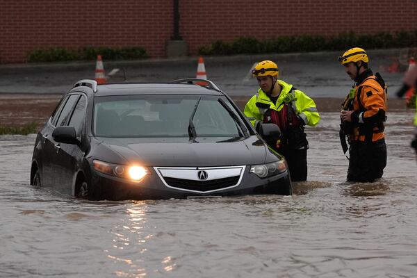 Santa Rosa firefighters attend to a submerged car in a flooded street during a storm Thursday, Nov. 21, 2024, in Santa Rosa, Calif. (AP Photo/Jeff Chiu)