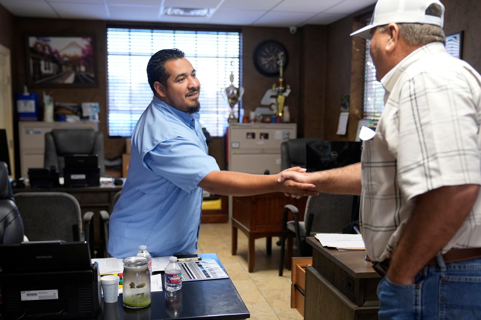 Ivan Barrera, left, shakes hands with Glen Hodge at the auto body shop Barrera works at in Lewisville, Texas, Wednesday, Oct. 2, 2024. (AP Photo/LM Otero)