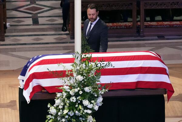 Jason Carter walks past the casket of his grandfather, former President Jimmy Carter, during a state funeral service at Washington National Cathedral in Washington, Thursday, Jan. 9, 2025. (AP Photo/Jacquelyn Martin)