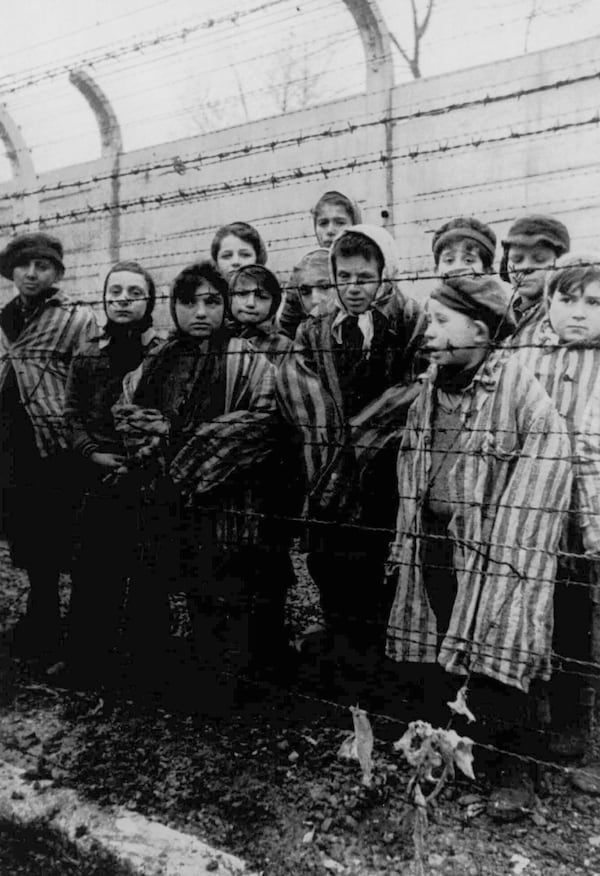 FILE - A picture taken just after the liberation by the Soviet army in January, 1945, shows a group of children wearing concentration camp uniforms behind barbed wire fencing in the Oswiecim (Auschwitz) nazi concentration camp. (AP Photo, File)