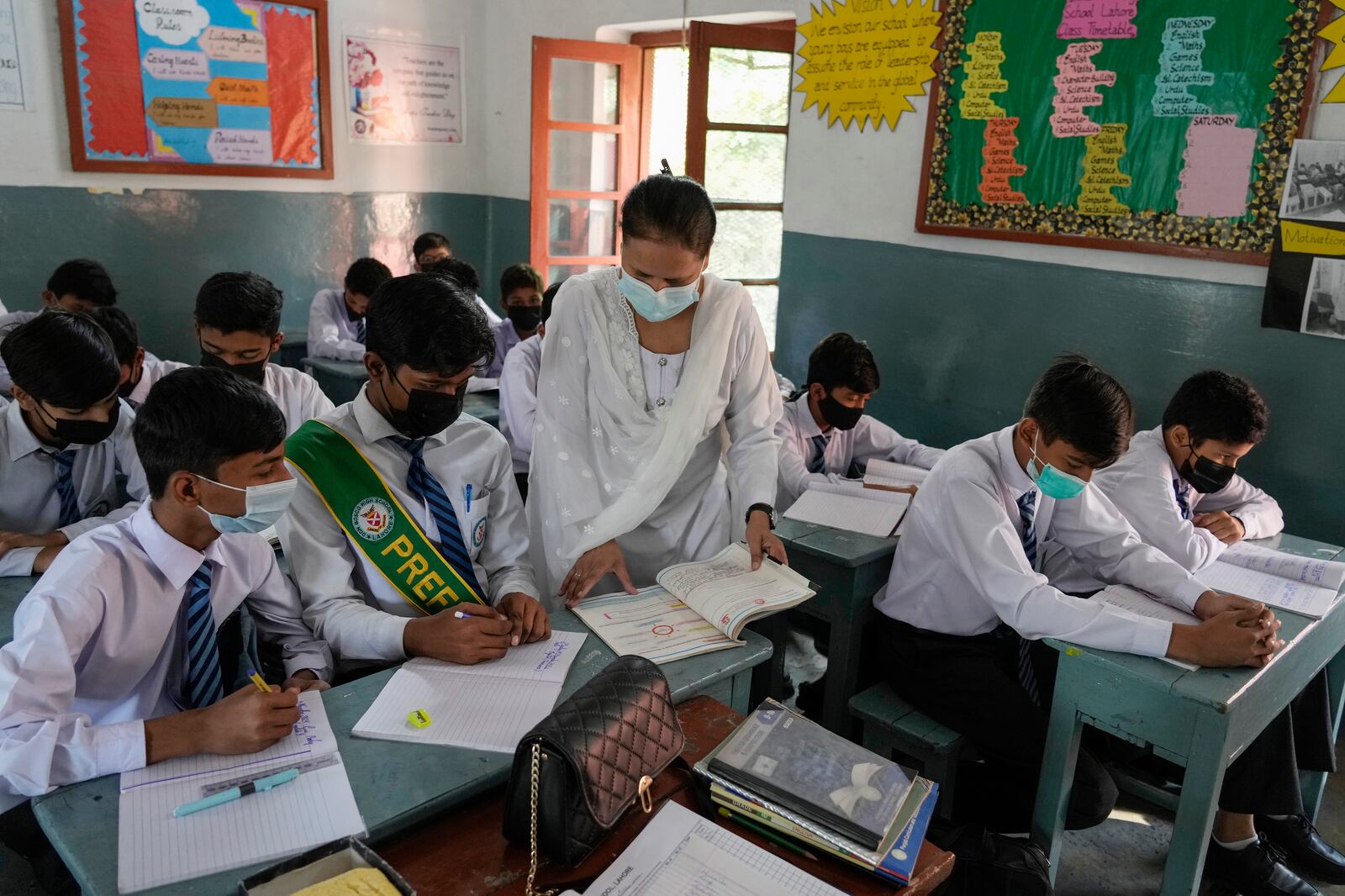 A teacher and students wear mask to protect themselves from poor air quality due to increasing smog in the city as they attend their school, in Lahore, Pakistan, Monday, Nov. 4, 2024. (AP Photo/K.M. Chaudary)