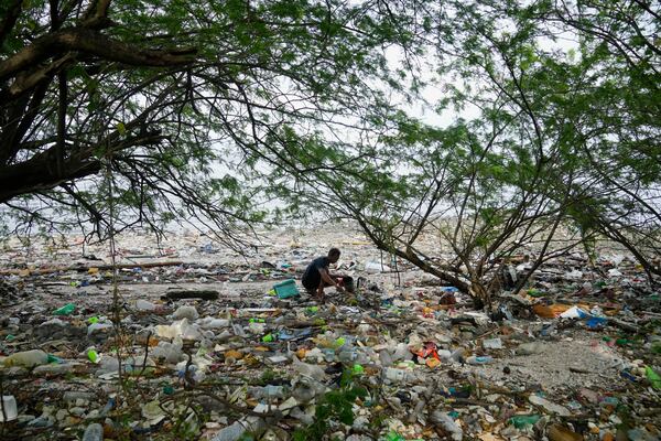 FILE - A man collects items along a polluted coastal area in Metro Manila, Philippines, Sept. 16, 2022. (AP Photo/Aaron Favila, File)