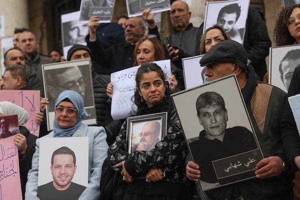 Wafaa Mustafa, center, holds a picture of her missing father during a demonstration in Damascus, Syria, Friday, Dec. 2024. The protesters demand accountability for members of Bashar Assad's government and military responsible for the detention, torture, or disappearance of their loved ones. (AP Photo/Ghaith Alsayed)