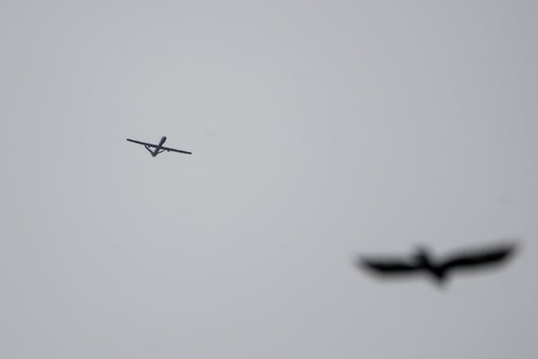 An Israeli drone flies while Israeli military vehicles guard a road where a military bulldozer operates in the West Bank refugee camp of Jenin, Wednesday, Jan. 22, 2025. (AP Photo/Majdi Mohammed)