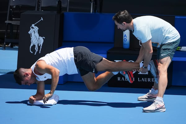 Spain's Carlos Alcaraz receives treatment from a trainer during a practice session ahead of the Australian Open tennis championship in Melbourne, Australia, Friday, Jan. 10, 2025. (AP Photo/Vincent Thian)