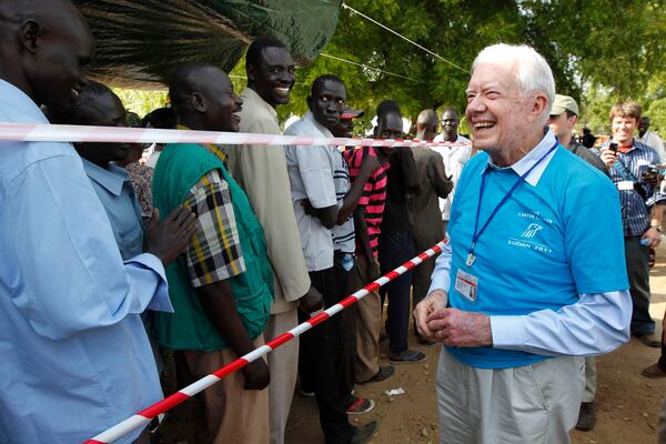 FILE - Former U.S. President Jimmy Carter, right, greets Southern Sudanese men waiting to cast their vote at a polling station in Juba, Southern Sudan, Jan 9, 2011, during a weeklong referendum on independence that is expected to split Africa's largest nation in two. (AP Photo/Jerome Delay, File)