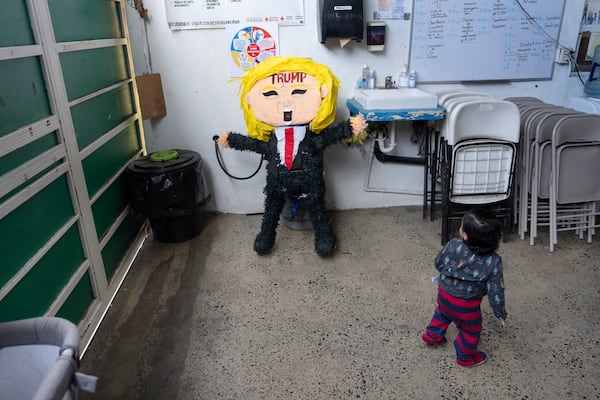 A child of a migrant family from the Mexican state of Guerrero looks at a piñata of President Donald Trump at a shelter for migrants Wednesday, Jan. 22, 2025, in the border city of Tijuana, Mexico. (AP Photo/Gregory Bull)