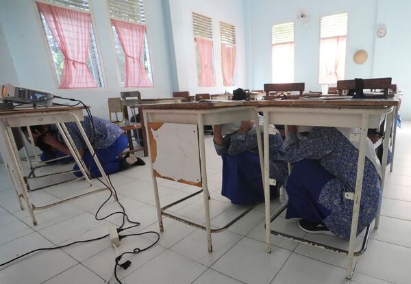 Students take cover under their desks during an earthquake drill at a school in Banda Aceh, Indonesia, Thursday, Dec. 12, 2024. (AP Photo/Achmad Ibrahim)