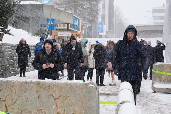 People leave the Congress Center where the World Economic Forum takes place during snowfall, in Davos, Switzerland, Thursday, Jan. 23, 2025. (AP Photo/Markus Schreiber)