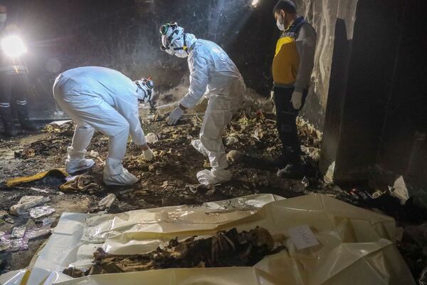 Syrian civil defense workers, known as the White Helmets, collect human remains found in two separate basements in Sbeneh, outskirts of Damascus, Syria, Tuesday, Jan. 28, 2025. According to the White Helmets, the charred remains belong to at least 26 victims of the Bashar Assad regime. (AP Photo/Omar Albam)