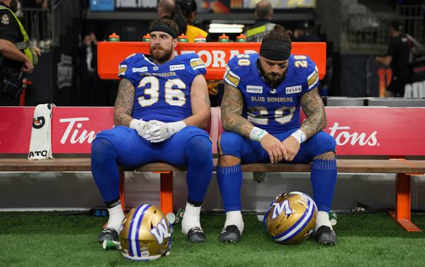 Winnipeg Blue Bombers' Bailey Feltmate (36) and teammate Brady Oliveira (20) sit on the bench after losing the 111th Grey Cup to the Toronto Argonauts, in Vancouver, British Columbia, Sunday, Nov. 17, 2024. (Ethan Cairns/The Canadian Press via AP)