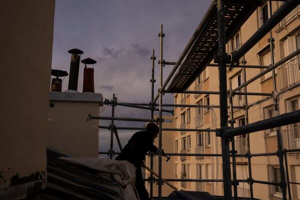 A roofer works on a building in Paris, Wednesday, Nov. 20, 2024. (AP Photo/Louise Delmotte)