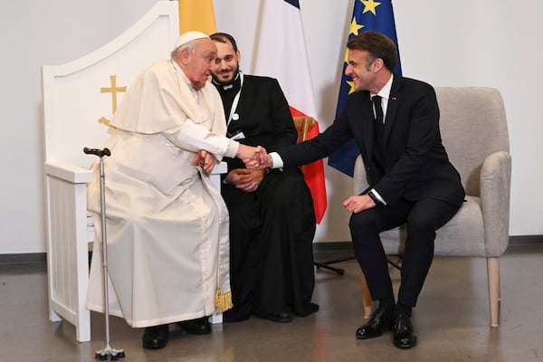 Pope Francis shakes hands with French President Emmanuel Macron in Ajaccio at the end of his one-day visit in the French island of Corsica, Sunday, Dec. 15, 2024. (Tiziana Fabi, Pool Via AP)