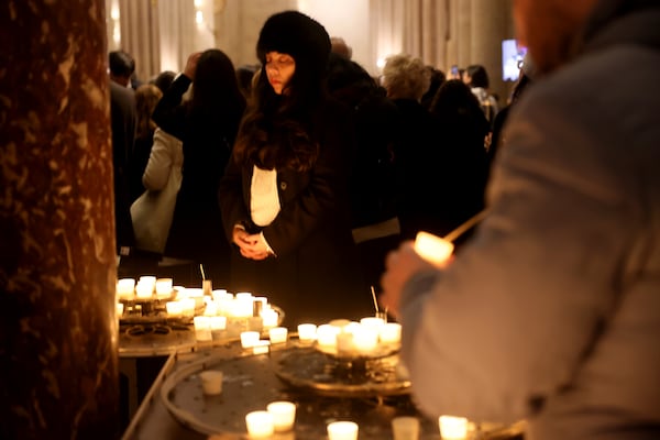 A woman prays by candles at Notre Dame Cathedral as the monument hosts Christmas Eve services for the first time since a devastating 2019 fire, Tuesday, Dec. 24, 2024 in Paris. (AP Photo/Thomas Padilla)