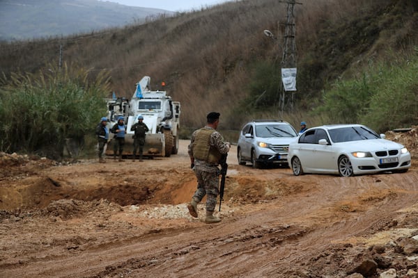 Motorists drive past a crater as Lebanese soldiers and UNIFIL peacekeepers secure the area in Khardali, southern Lebanon, following a ceasefire between Israel and Hezbollah on Wednesday, Nov. 27, 2024. (AP Photo/Mohammed Zaatari)