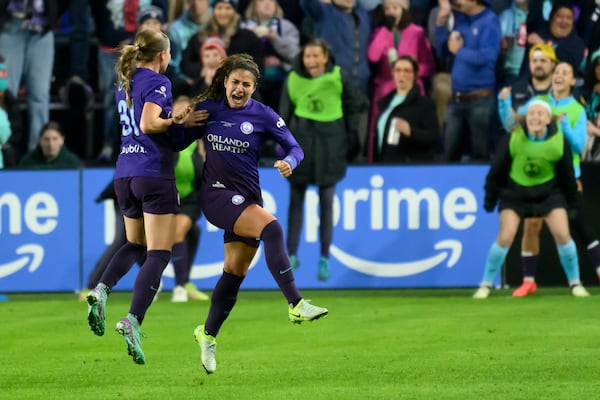 Orlando Pride midfielder Angelina, center, celebrates her assist on a goal by Pride forward Barbra Banda with teammate Pride defender Cori Dyke (31) during the first half of the NWSL championship at CPKC Stadium against the Washington Spirit, Saturday, November 23, 2024, in Kansas City, Mo. (AP Photo/Reed Hoffmann)