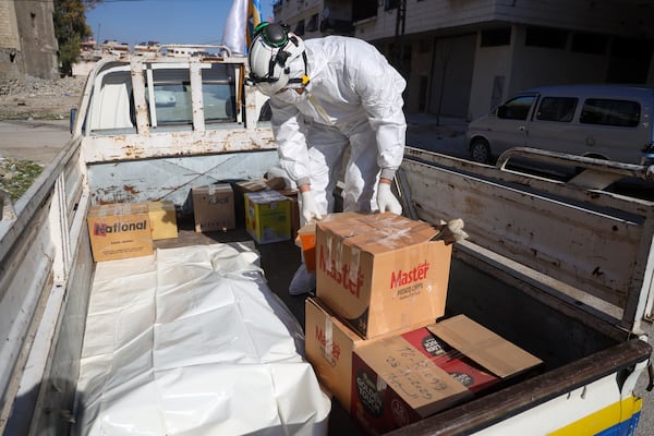 Syrian civil defense workers, known as the White Helmets, load in a pick-up truck boxes containing human remains found in two separate basements in Sbeneh, outskirts of Damascus, Syria, Tuesday, Jan. 28, 2025. According to the White Helmets, the charred remains belong to at least 26 victims of the Bashar Assad regime. (AP Photo/Omar Albam)