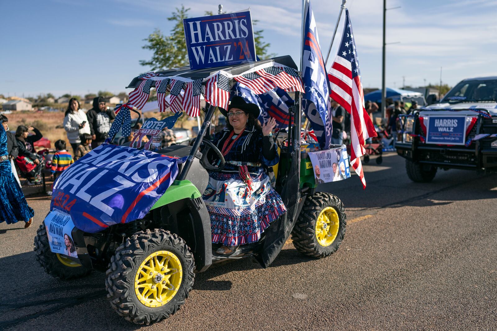 A Navajo woman waves as she campaigns for presidential hopeful Kamala Harris in a caravan of Democratic-themed floats, at the Western Navajo Fair in Tuba City, Ariz., Saturday, Oct. 19, 2024. Natives, which make up 5.2% of the state’s population, voted in big numbers for the Democratic party in 2020 and were credited with swinging the state blue for the first time in decades. (AP Photo/Rodrigo Abd)