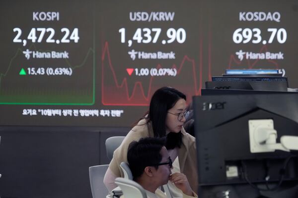 Currency traders watch monitors near a screen showing the Korea Composite Stock Price Index (KOSPI), top left, and the foreign exchange rate between U.S. dollar and South Korean won, top center, at the foreign exchange dealing room of the KEB Hana Bank headquarters in Seoul, South Korea, Wednesday, Dec. 18, 2024. (AP Photo/Ahn Young-joon)