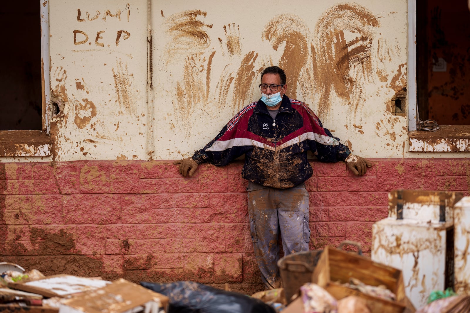 A man looks at the damage and debris in front of a house a affected by floods in Alfafar, Spain, on Monday, Nov. 4, 2024. (AP Photo/Manu Fernandez)