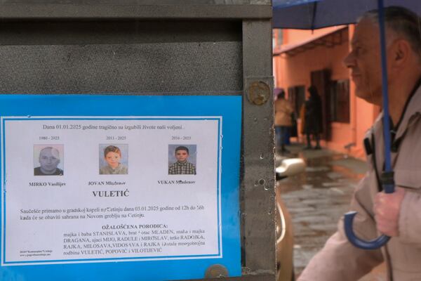 A man walks past death notices of victims of a shooting in Cetinje, 36 kilometers (22 miles) west of Podogrica, Montenegro, Friday, Jan 3, 2025. (AP Photo/Risto Bozovic)