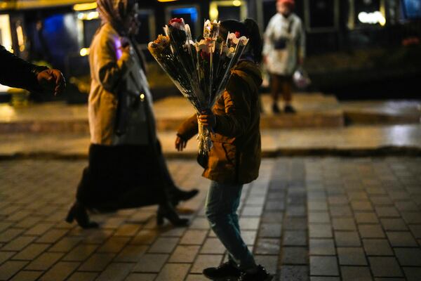 A girl sells flowers to passersby on the Karakoy sea promenade in Istanbul, Turkey, Friday, Dec. 6, 2024. (AP Photo/Francisco Seco)