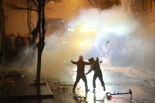 A demonstrator throws a bottle toward police as protesters rally against the government's decision to suspend negotiations on joining the European Union for four years, outside the parliament's building in Tbilisi, Georgia, early Sunday, Dec. 1, 2024. (AP Photo/Zurab Tsertsvadze)