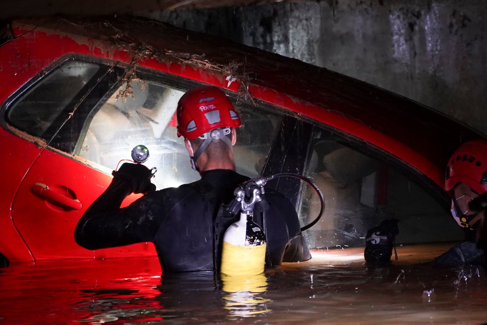 Civil Guards walk in a flooded indoor car park to check cars for bodies after floods in Paiporta, near Valencia, Spain, Monday, Nov. 4, 2024. (AP Photo/Alberto Saiz)