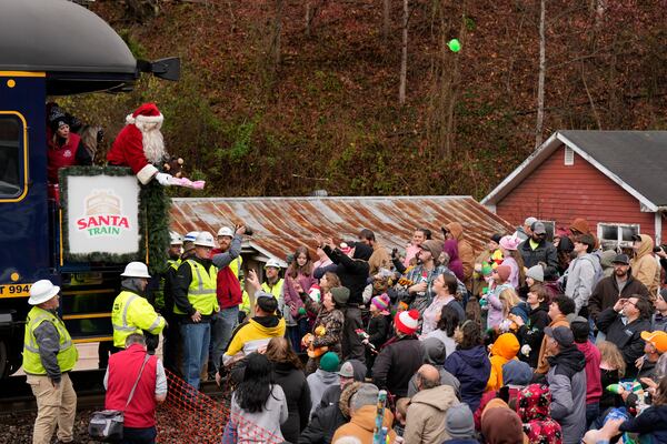 Santa Claus tosses toys to people during the 82nd run of the CSX Santa Train, Saturday, Nov. 23, 2024, in Dante, Va. (AP Photo/George Walker IV)