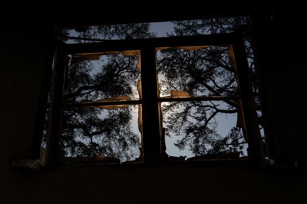 Burned trees are seen through a broken and charred window in the aftermath of the Eaton Fire, Monday, Jan 13, 2025, in Altadena, Calif. (AP Photo/Carolyn Kaster)