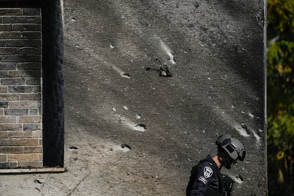 A police bomb squad officer inspects the site where a rocket fired from Lebanon landed in a backyard in Kiryat Shmona, northern Israel, Tuesday Nov. 26, 2024. (AP Photo/Leo Correa)