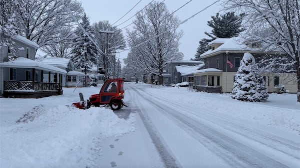 A person clears the snow from the sidewalk in Lowville, N.Y., on Saturday, Nov. 30, 2024. (AP Photo/Cara Anna)