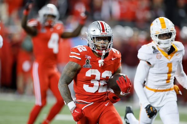 Ohio State running back TreVeyon Henderson, front, scores a touchdown against Tennessee during the second half in the first round of the College Football Playoff, Saturday, Dec. 21, 2024, in Columbus, Ohio. (AP Photo/Jay LaPrete)