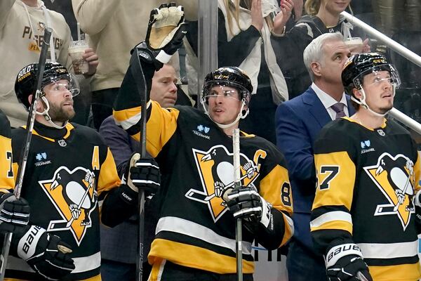 Pittsburgh Penguins' Sidney Crosby, center, acknowledges the crowd after surpassing Mario Lemieux for the franchise record for most assists during the second period of an NHL hockey game against the New York Islanders, Sunday, Dec. 29, 2024, in Pittsburgh. (AP Photo/Matt Freed)