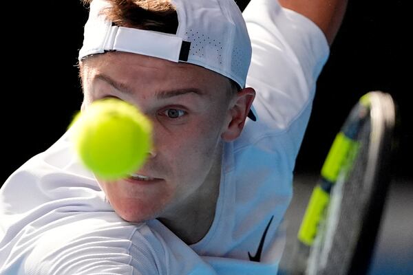 Holger Rune of Denmark plays a backhand return to Jannik Sinner of Italy during their fourth round match at the Australian Open tennis championship in Melbourne, Australia, Monday, Jan. 20, 2025. (AP Photo/Asanka Brendon Ratnayake)