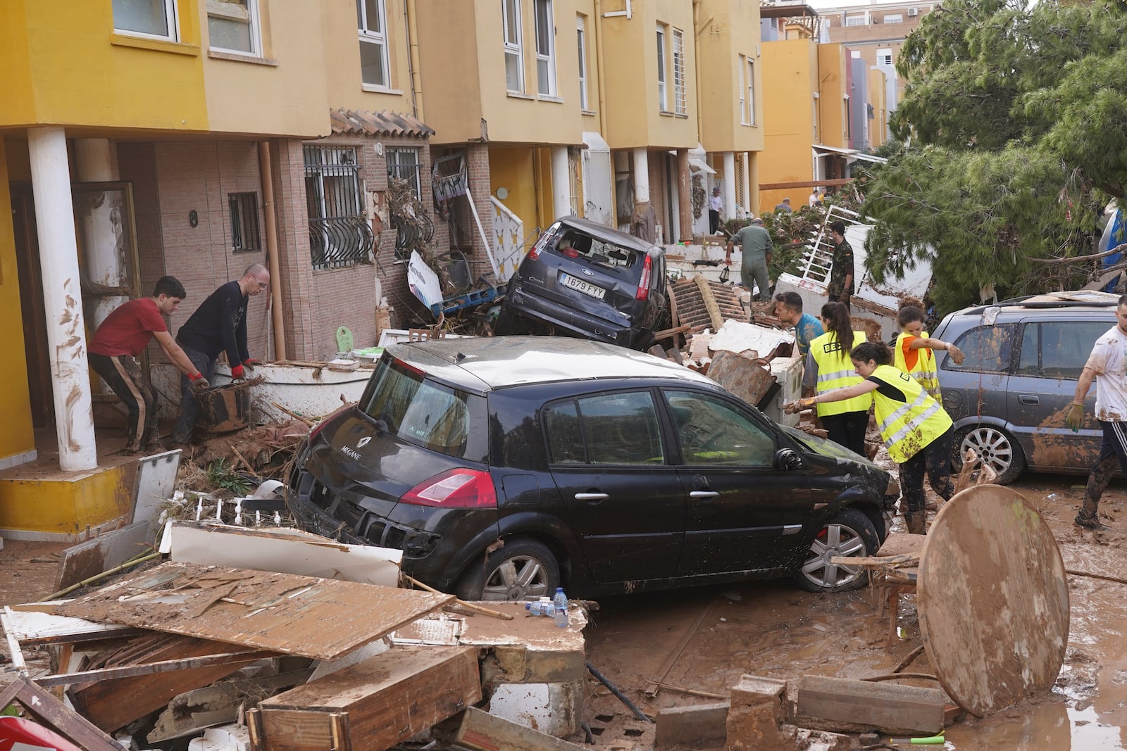 People clear debris from the street after floods in Massanassa, just outside of Valencia, Spain, Friday, Nov. 1, 2024. (AP Photo/Alberto Saiz)