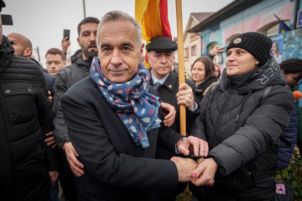 Calin Georgescu, center, an independent candidate for president who won the first round of presidential elections shakes with a supporter outside a closed voting station after Romania's Constitutional Court annulled the first round of presidential elections, in Mogosoaia, Romania, Sunday, Dec. 8, 2024. (AP Photo/Vadim Ghirda)