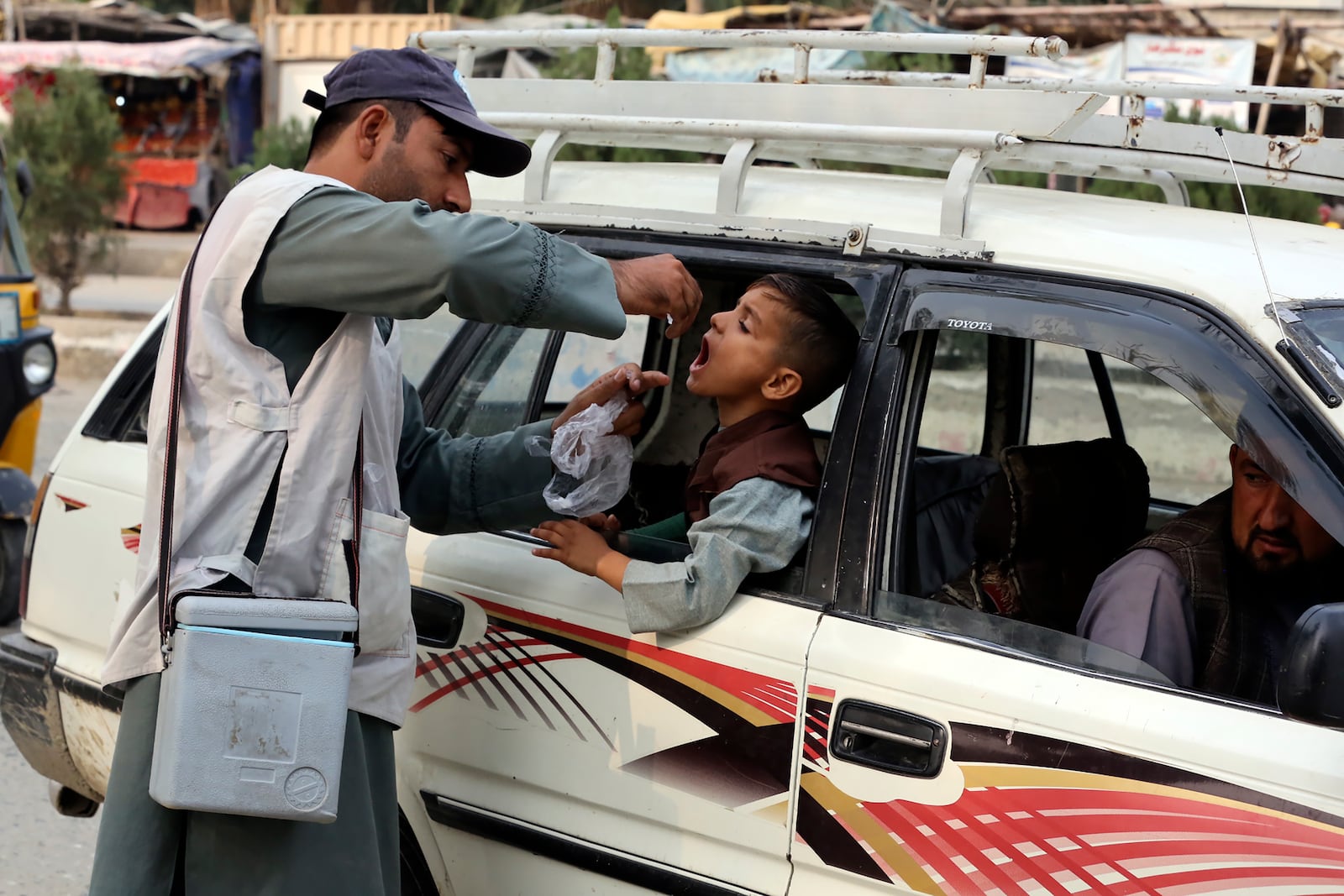 A health worker administers a polio vaccine to a child inside a Taxi in the city of Jalalabad, east of Kabul, Afghanistan, Tuesday, Oct. 29, 2024. (AP Photo/Shafiullah Kakar)