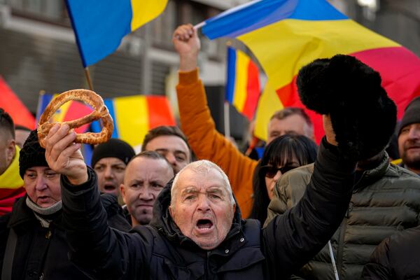 A protester holding a bagel in one hand shouts slogans during a rally organized by the right wing Alliance for the Unity of Romanians (AUR), calling for free elections after Romania' s Constitutional Court annulled the first round of presidential elections last December, in Bucharest, Romania, Sunday, Jan. 12, 2025.(AP Photo/Vadim Ghirda)