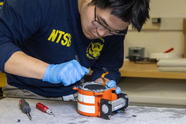 National Transportation Safety Board (NTSB) investigators examine cockpit voice recorder and flight data recorder recovered from the American Airlines passenger jet that crashed with an Army helicopter Wednesday night near Washington, D.C, Thursday, Jan.30, 2024. (NTSB via AP)