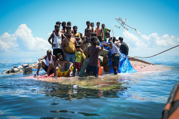 Ethnic Rohingya refugees stand on their capsized boat as rescuers throw a rope to them off West Aceh, Indonesia, on March 21, 2024. (AP Photo/Reza Saifullah)