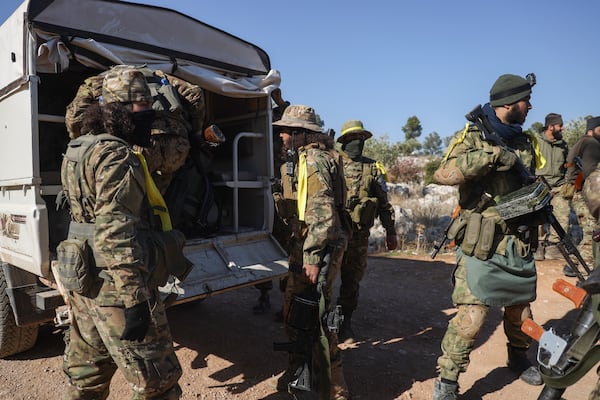 Syrian opposition soldiers get off a truck as they enter areas controlled by the Assad regime in Anjara, western outskirts of Aleppo, Syria, Thursday Nov. 29, 2024. Syrian armed groups launched a large-scale attack on areas controlled by government forces and seized territory in northwestern Syria, opposition groups said Thursday.(AP Photo/Omar Albam)