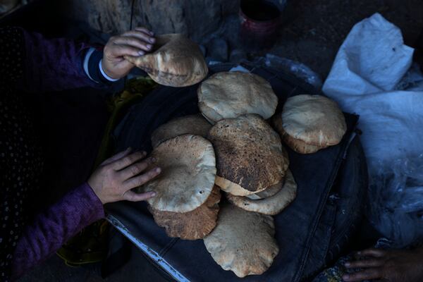 A Palestinian woman sorts through fresh bread amid dire food shortages in Deir al-Balah, Gaza Strip, Monday, Dec. 2, 2024. (AP Photo/Abdel Kareem Hana)