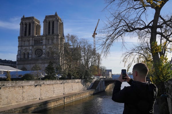 A man takes a picture of Notre-Dame cathedral as French President Emmanuel Macron visits the renovated cathedral, Friday, Nov. 29, 2024 in Paris. (AP Photo/Michel Euler)