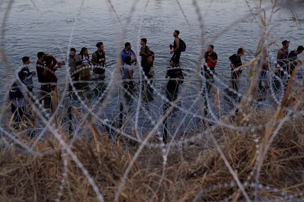 FILE - Migrants wait to climb over concertina wire after they crossed the Rio Grande and entered the U.S. from Mexico on Sept. 23, 2023, in Eagle Pass, Texas. (AP Photo/Eric Gay, File)