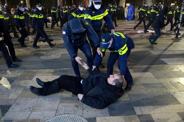 Police officers help a man get up as they push protesters away after destroying a tent camp on a street during a rally against the results of the parliamentary elections amid allegations that the vote was rigged in Tbilisi, Georgia, Tuesday, Nov. 19, 2024. (AP Photo/Zurab Tsertsvadze)